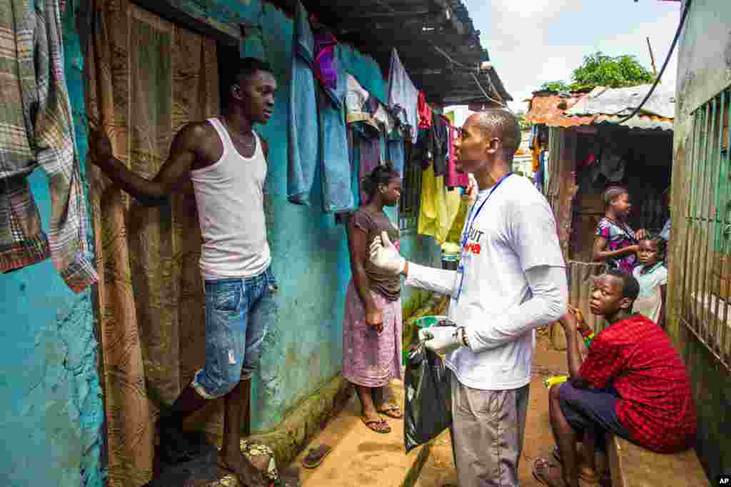 A health worker volunteer talks with a resident on how to prevent and identify the Ebola virus in others, and distributes bars of soap in Freetown, Sierra Leone, Sept. 20, 2014.
