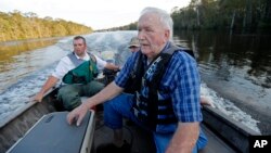 William Larymore, left, of the South Carolina Department of Natural Resources, and Salvatore Cirencione, of the State Law Enforcement Division, partially visible behind, help resident Franklin Bessemer, who lives on the river, back to a pier on the Waccamaw River in Conway, South Carolina, Sept. 17, 2018. Bessemer's boat had quit while he was checking on his home.