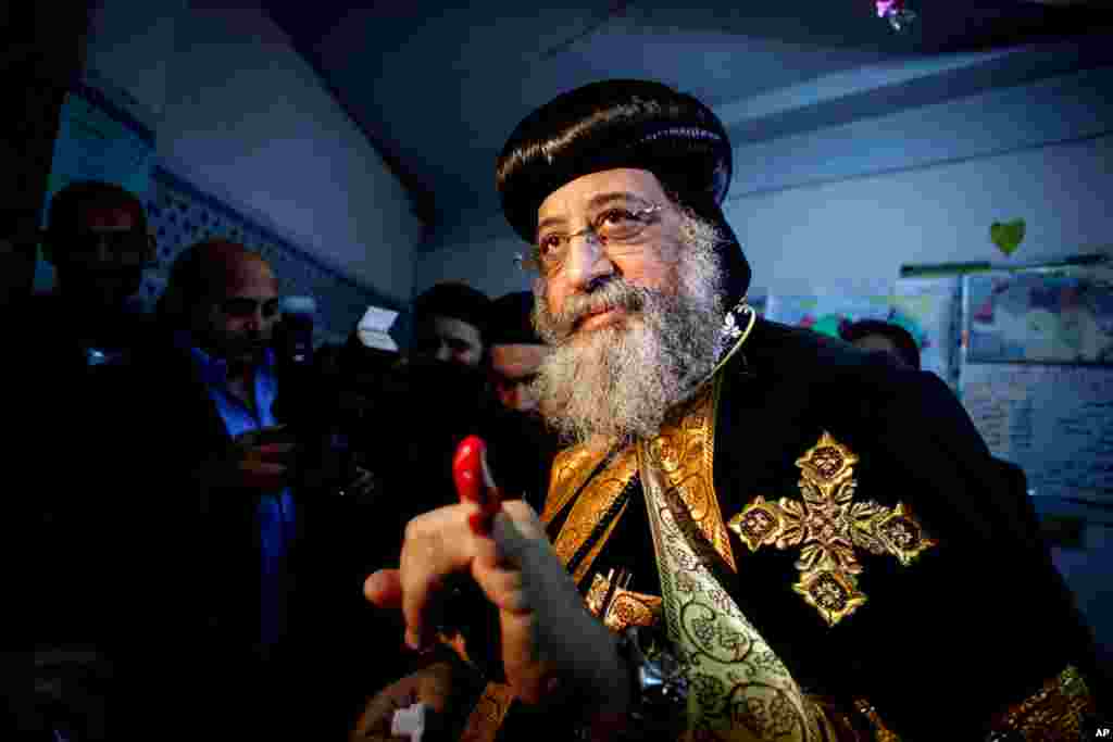 Pemimpin umat Kristen Koptik Paus Tawadros II menunjukkan jarinya yang bertinta setelah memberikan suara dalam referendum di sebuah TPS di Kairo (14/1). (AP/Eman Helal)