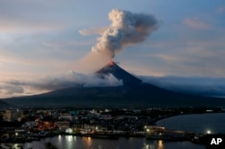 With Legazpi city in foreground, the Mayon volcano erupts anew at dusk, Jan. 25, 2018, in Albay province about 200 miles (340 kilometers) southeast of Manila, Philippines.