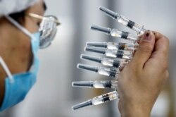 FILE - A worker performs a quality check in the packaging facility of Chinese vaccine maker Sinovac Biotech, developing an experimental COVID-19 vaccine, during a government-organized media tour in Beijing, China, Sept. 24, 2020.