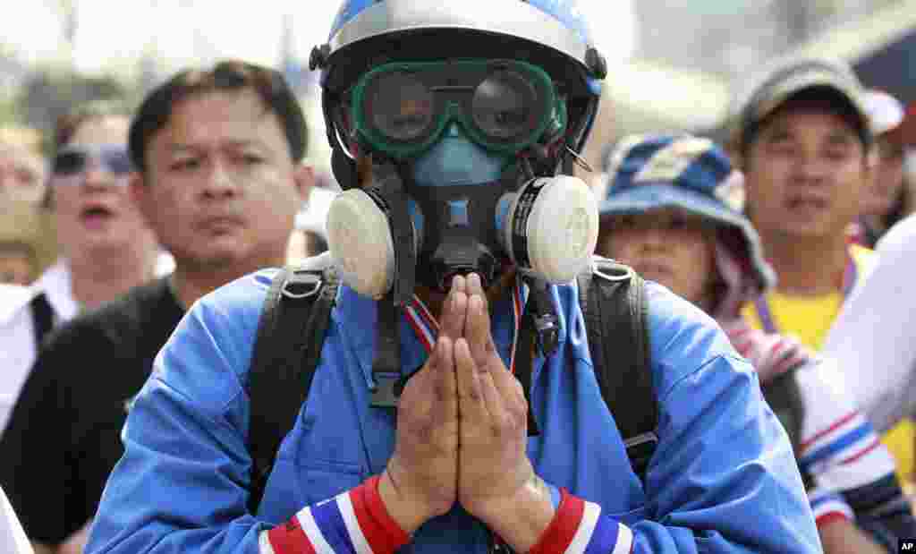 Seorang pria berdoa saat ia dan para koleganya mengkonfrontasi polisi dalam operasi pengambilalihan kantor-kantor pemerintah yang diduduki para demonstran anti-pemerintah di pinggiran kota Bangkok (14/2). (AP/Wason Wanichakorn)