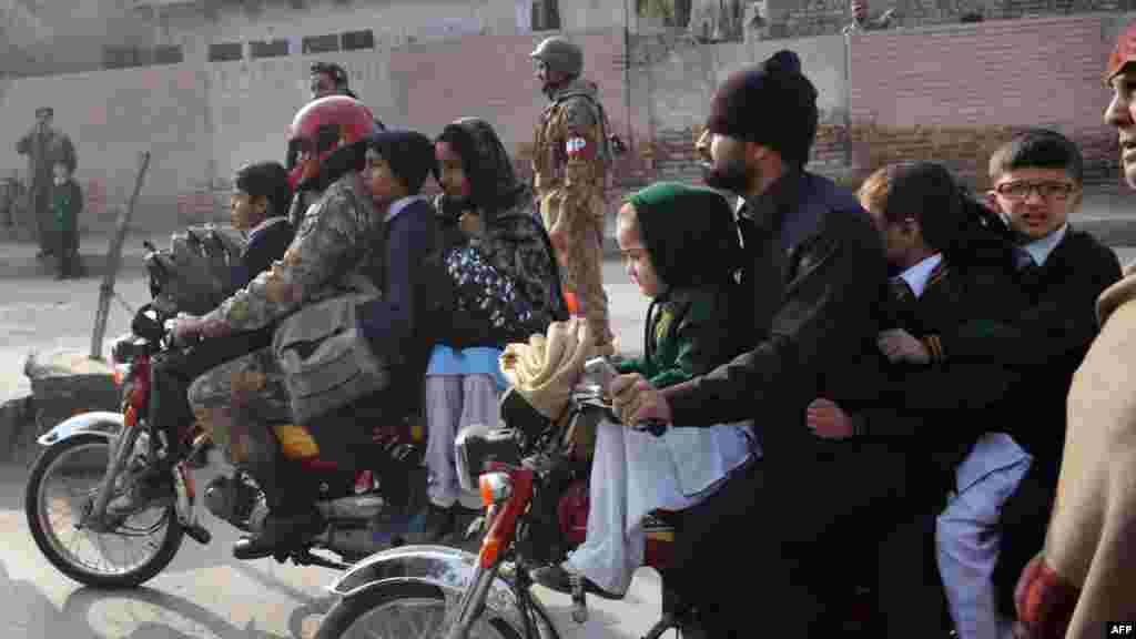 Des parents pakistanais quittent avec leurs enfants à proximité du lieu d'une attaque par des hommes armés talibans sur une école à Peshawar, le 16 décembre 2014.