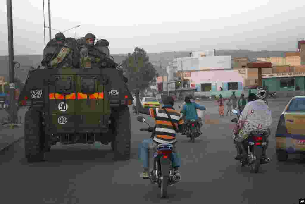 A motorcyclist waves his support as French troops in two armored personnel carriers drive through Mali's capital Bamako on the road to Mopti, January 15, 2013.