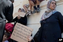 FILE - Stranded migrants and refugees hold placards as they protest outside the German Embassy in Athens.