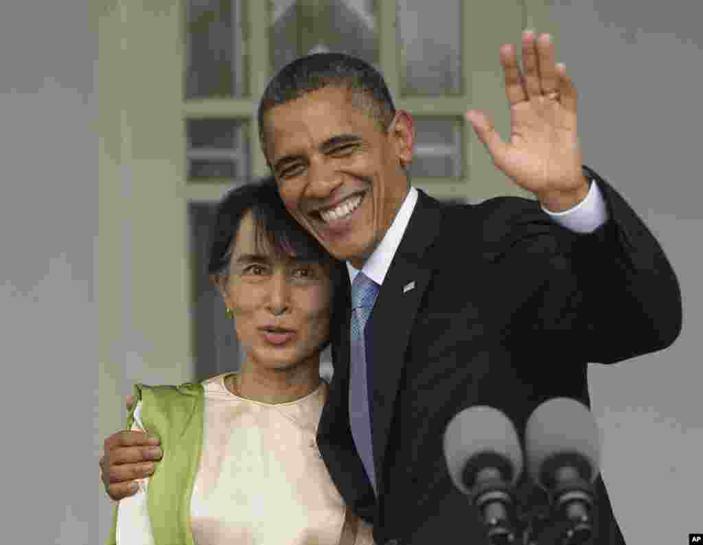 US President Barack Obama, right, waves as he embraces Burmese democracy activist Aung San Suu Kyi after addressing members of the media at her residence in Rangoon, Burma, November 19, 2012.