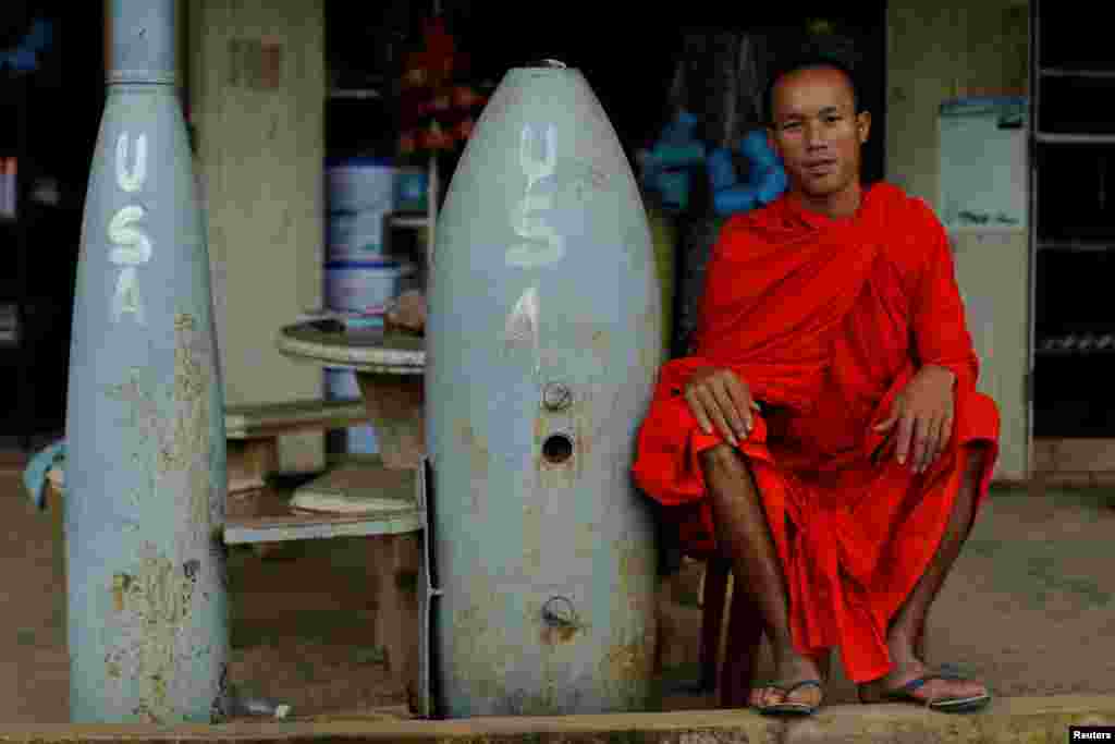 ព្រះសង្ឃពុទ្ធសាសនាមួយអង្គឈរជិតគ្រាប់បែកមិនទាន់ផ្ទុះ ដែលត្រូវបានទម្លាក់ដោយកងកម្លាំងដែនអាកាសអាមេរិកនៅអំឡុងពេលសង្រ្គាមវៀតណម ក្នុងក្រុង Xieng Khouang ប្រទេសឡាវ។