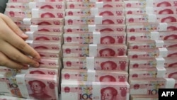 A teller counts yuan banknotes in a bank in Lianyungang, east China's Jiangsu province, Aug. 11, 2015. 