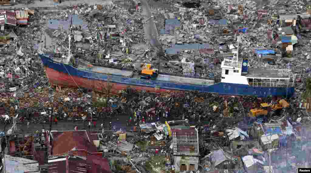 Warga setempat menonton rongsokan sebuah kapal yang tersapu oleh topan Haiyan hampir dua minggu yang lalu, di kota Tacloban, Filipina tengah.