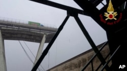 This photo released by the Italian firefighters, shows a truck stopped where the Morandi highway bridge collapsed in Genoa, Aug. 14, 2018. 