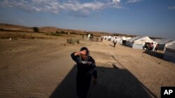 A woman walks at a refugee camp in Nea Kavala, northern Greece, Tuesday, Sept. 3, 2019.