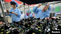 FILE - Employees work on a FiberHome Technologies Group factory production line in Wuhan, Hubei province, China, July 27, 2015. China relaxed its one-child policy Oct. 29, in part, to try to offset the country’s shrinking workforce.
