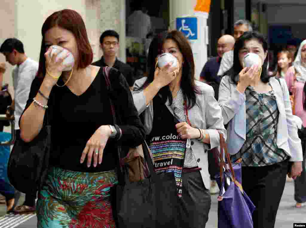Women cover their faces with masks as haze shrouds Singapore's central business district.