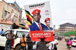 A supporter of Ugandan opposition Presidential candidate Robert Kyagulanyi also known as Bobi Wine, carry his electoral campaign poster ahead of the presidential and parliamentary elections, in Kampala, Uganda, Jan. 12, 2021.
