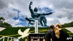 People stand in front of the cenotaph and the Peace statue after the ceremony marking the 75th anniversary of the atomic bombing of Nagasaki, at the Nagasaki Peace Park on August 9, 2020. - Nagasaki was flattened in an atomic inferno three days…