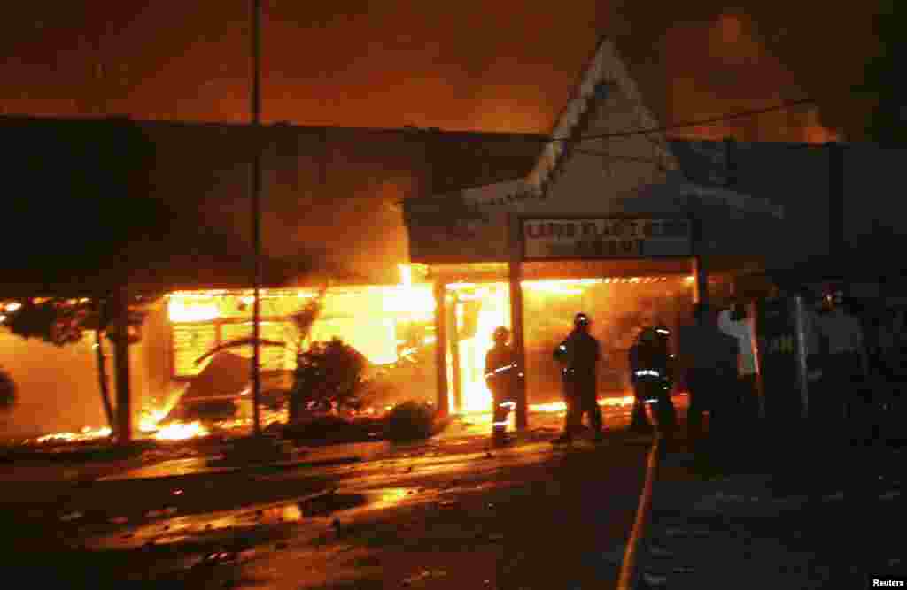 Firefighters and police officers stand outside Tanjung Gusta prison, which was set ablaze by inmates after a riot broke out, in Medan, North Sumatra province, July 11, 2013. 