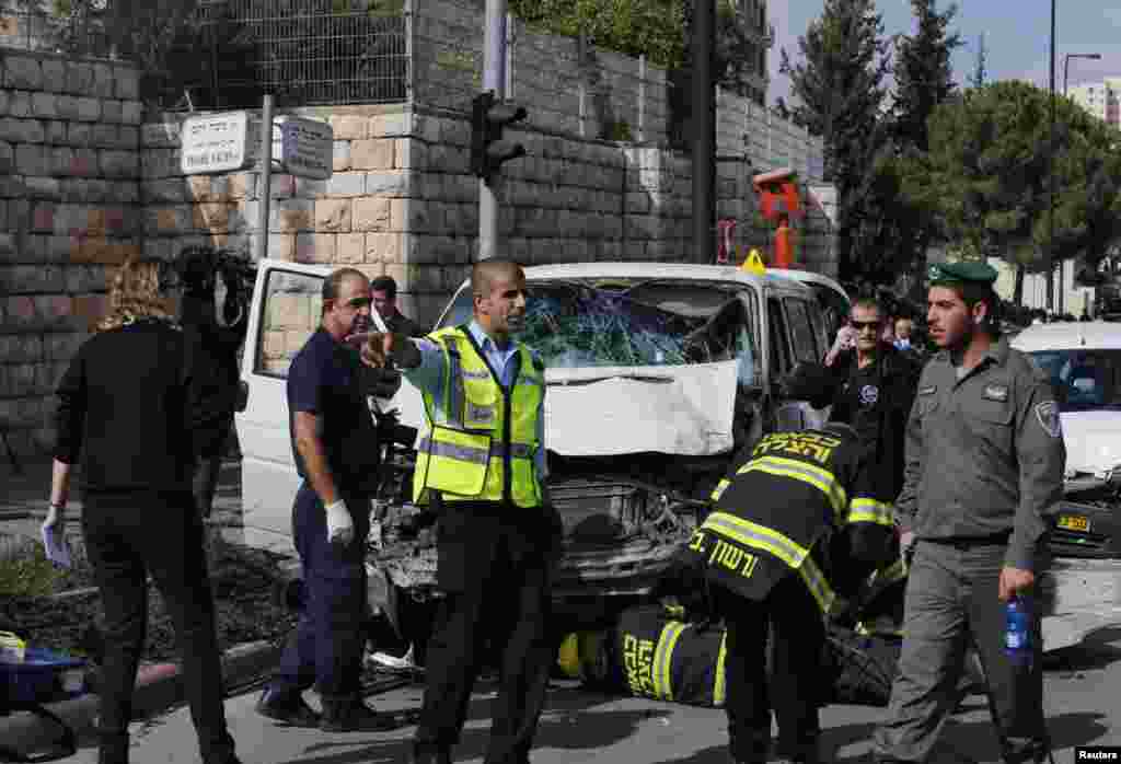 An Israeli police officer gestures in front of the vehicle of a Palestinian motorist who rammed into pedestrians at the scene of the attack in Jerusalem, Nov. 5, 2014.