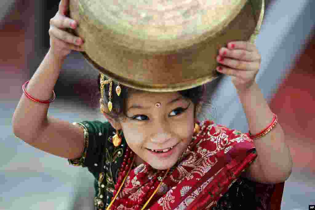 កុមារី​ម្នាក់​ក្នុង​សំលៀកបំពាក់​ប្រពៃណី​លេង​ជាមួយ​នឹង​ចានដែក​ ខណៈ​ពេល​រង់ចាំ​ការ​ចាប់ផ្តើម​ពិធី​ Kumari Puja នៅ​វិហារ Hanuman Dhoka ក្នុង​រដ្ឋធានី​កាតម៉ានឌូ ប្រទេស​នេប៉ាល់។&nbsp;