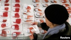FILE - A customer picks fish fillet as she visits the fish department of a hypermarket of French grocery retailer Auchan in Moscow, January 15, 2015.