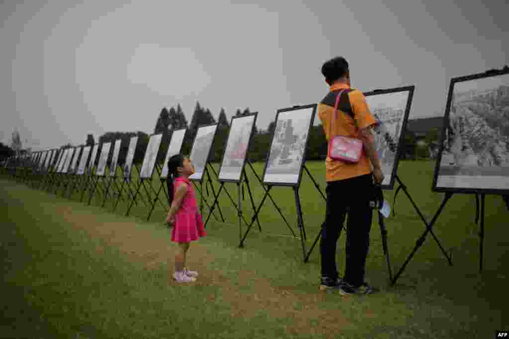 A South Korean girl listens to her grandfather as they stand before a photo exhibition of the Korean War at the National Cemetery in Seoul as the country marks the 64th anniversary of the start of the Korean War.