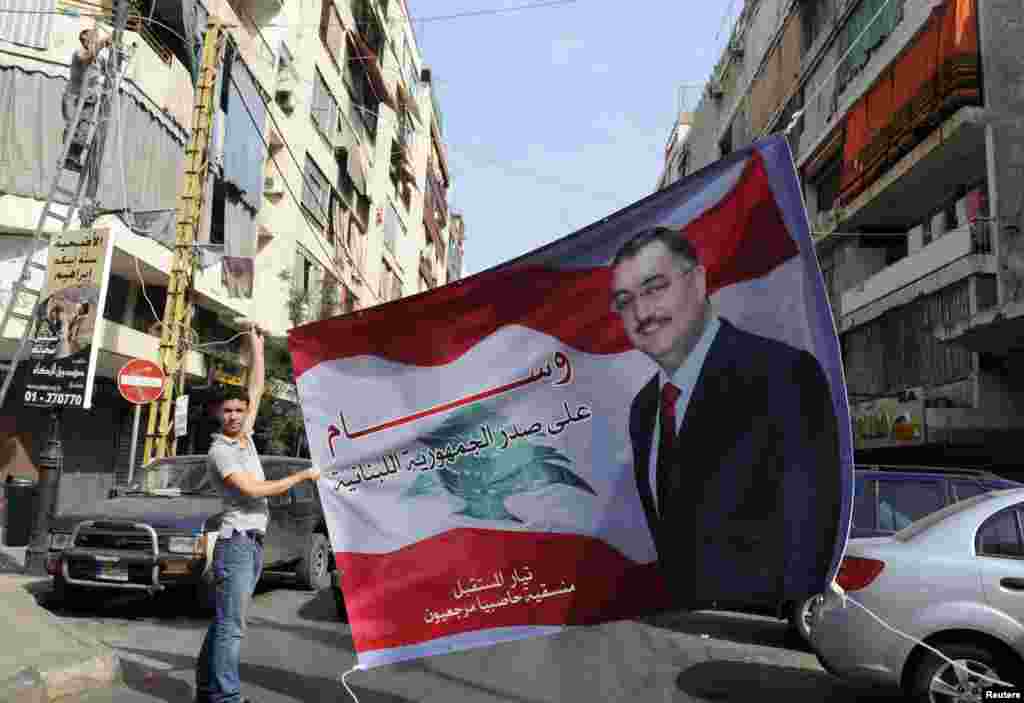 A Sunni Muslim man hangs up a poster with an image of senior intelligence official Wissam al-Hassan, in the Tariq al-Jadideh district in Beirut, October 20, 2012.