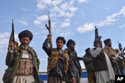FILE - Afghan militia men raise their weapons as they stand guard in the Achin district of Nangarhar province east of Kabul, Afghanistan, Dec. 27, 2015.