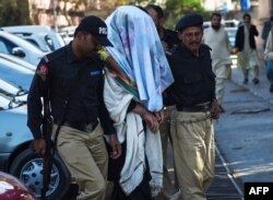 Pakistani policemen escort an arrested founding member of an ethnic Pashtun movement, Alamzeb Mehsud, with his face covered, at a court in Karachi, Jan. 22, 2019. He was arrested the day before on terrorism charges and for making anti-government speeches, police said.
