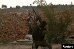 FILE - Syrian Democratic Forces (SDF) fighters shoot a drone they said belonged to Islamic State fighters on the bank of the Euphrates river, west of Raqqa city, Syria, April 8, 2017.