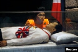 FILE - Former Philippine first lady Imelda Marcos kisses the glass coffin of her husband, late dictator Ferdinand Marcos, who remains unburied since his death in 1989, in the town of Batac, Ilocos Norte province, north of Manila, March 26, 2010.