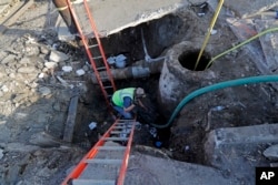 Workers fix a sewer main below the sidewalk in Mid City New Orleans, Jan. 31, 2018. City officials say New Orleans needs more than $11 billion to update key parts of its infrastructure but has about $2 billion in hand.