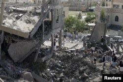 Houthi militants gather on the rubble of the offices of the education ministry's workers union, destroyed by Saudi-led airstrikes, in Yemen's northwestern city of Amran, August 19, 2015.