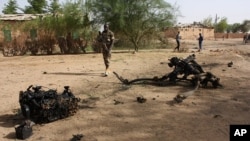 (Photo d’archives) Des soldats nigériens marchent près des débris après une attaque-suicide à l'intérieur d'une caserne militaire, à Agadez, dans le nord du Niger, le jeudi 23 mai 2013.