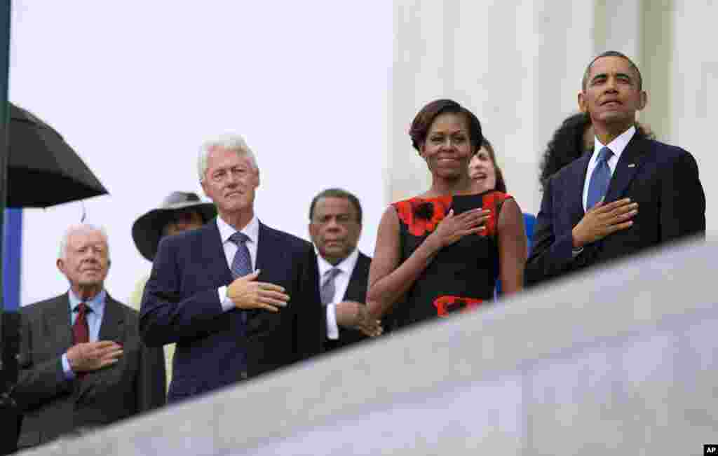 From left, former President Jimmy Carter, former President Bill Clinton, former U.N. Ambassador Andrew Young, first lady Michelle Obama, and President Barack Obama stand for the national anthem during a ceremony commemorating the 50th anniversary of the March on Washington, Aug. 28,2013.