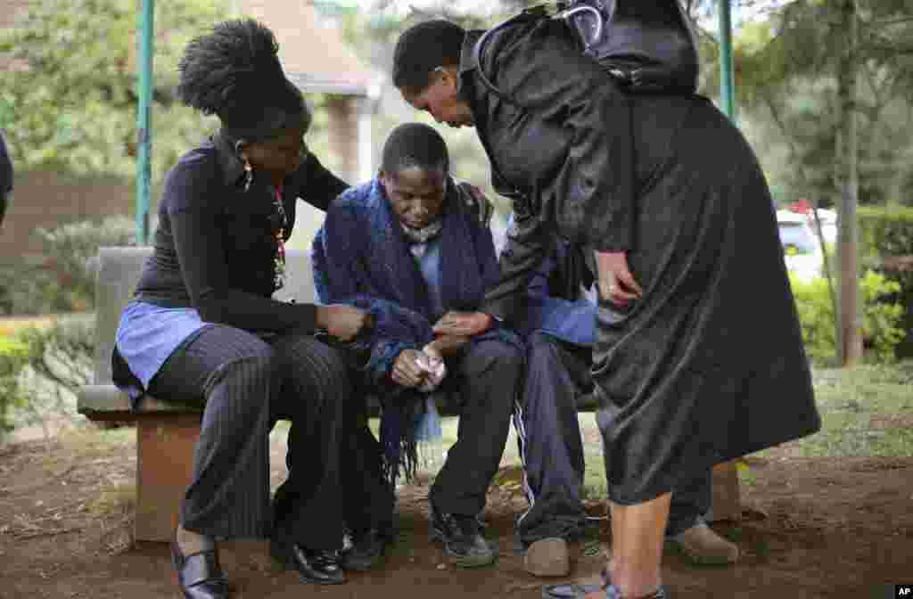 Stephen, center, who lost his father in Saturday's attack at the Westgate Mall in Nairobi, Kenya, is comforted by relatives as he waits for the post mortem exam at the city morgue, Sept. 23, 2013.