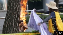 Seorang pria Korea Selatan (kiri) membakar diri di depan Kedutaan Jepang di Seoul (kiri), sementara seorang perempuan berupaya memadamkan api (12/8).