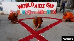 FILE - Buddhist monks light candles during an HIV/AIDS awareness campaign for World AIDS Day in Kolkata, India, Dec. 1, 2018. 