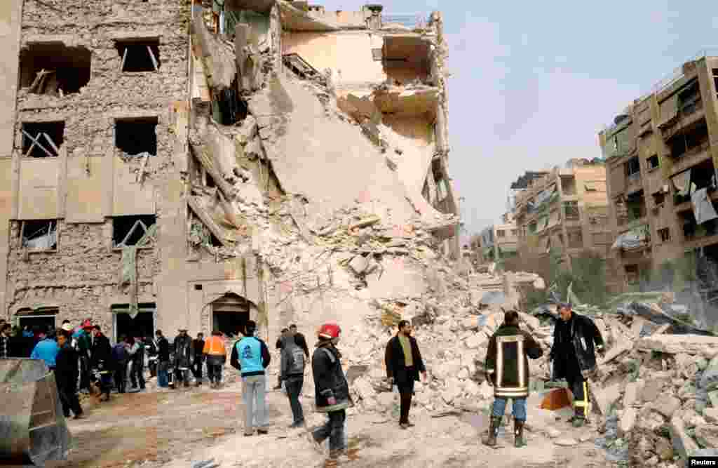 Syrian security personnel, members of the civil defence and civilians gather at the site where a large blast hit a neighborhood of Aleppo, January 18, 2013.