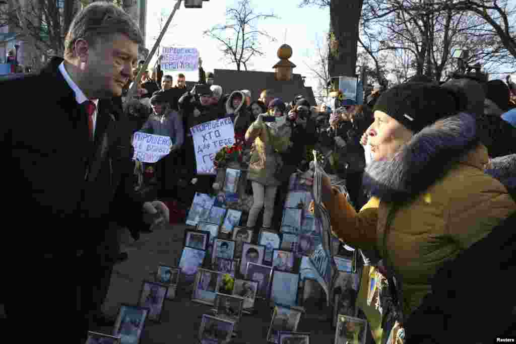 Ukrainian President Petro Poroshenko talks with a woman during a wreath laying ceremony at the monument to the fallen heroes of the "Heavenly Sotnya" (Hundred) in Kyiv, Nov. 21, 2014.