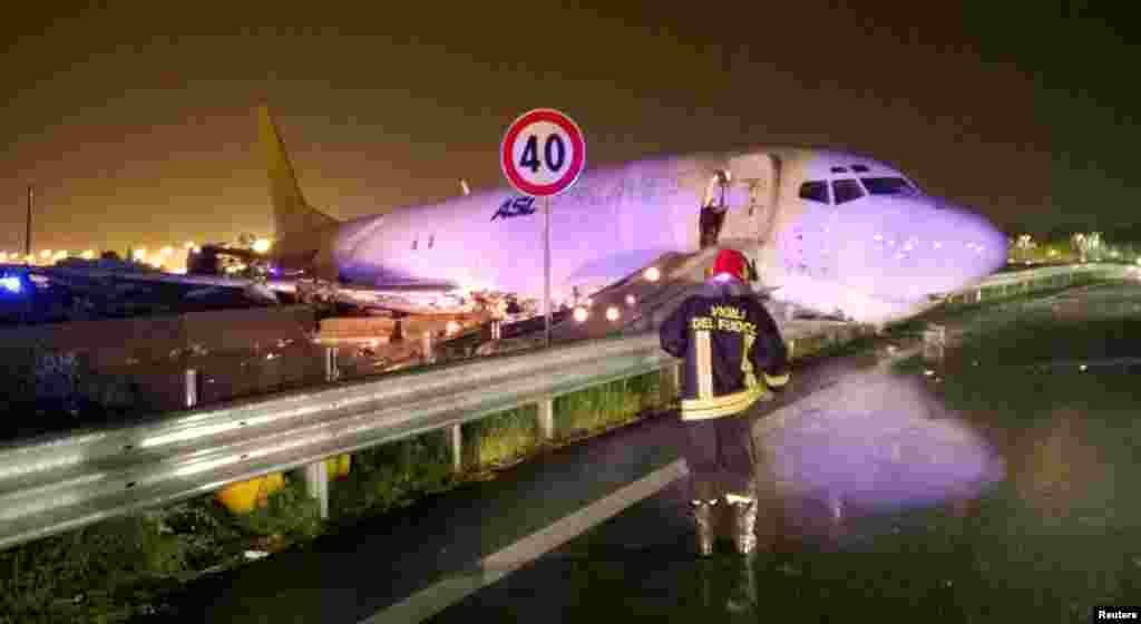 A firefighter stands in front of a cargo plane that exited the runway after sliding onto a local road in Orio al Serio, next to Milan, Italy, in this handout picture provided by Italy's Fire Fighters.