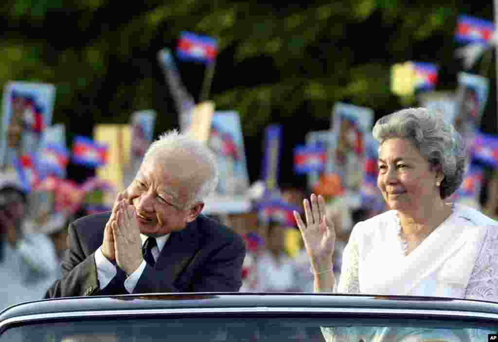 Then King Sihanouk and Queen Monique greet well-wishers from a limousine after a ceremony ending three official days celebrating Cambodia's 50 years of Independence in capital Phnom Penh, November 11, 2003.