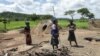 Members of a family stand next to their grass-hut dwelling which was destroyed by the police at Manzou Farm in Mazoe, north of Harare, in Zimbabwe, Jan. 15, 2015.