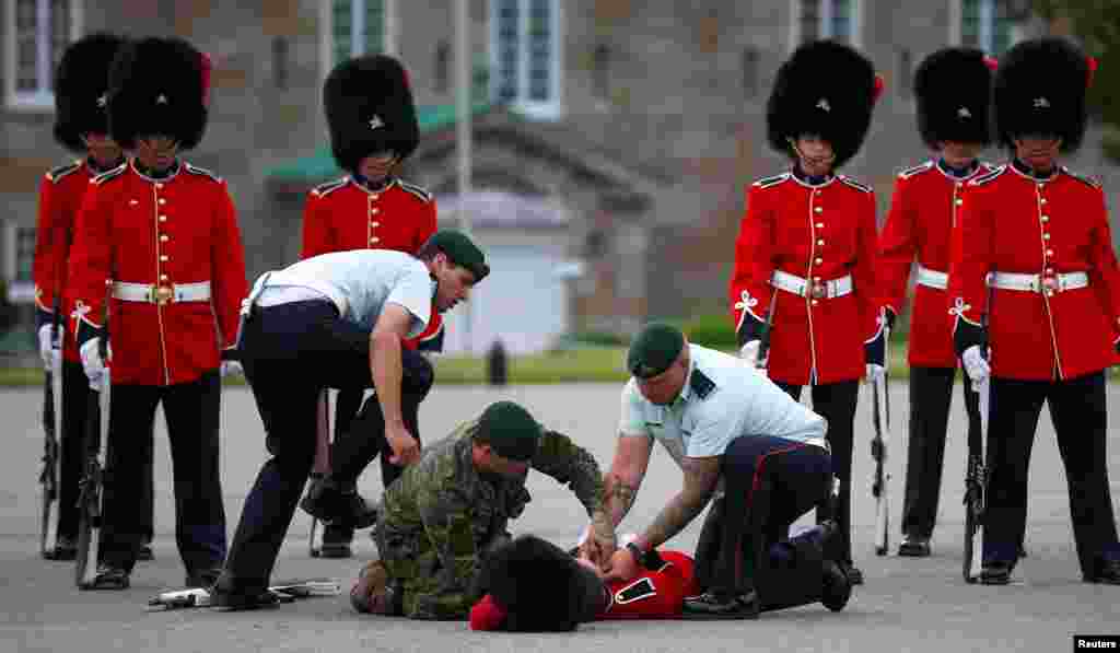 A member of the honor guard is attended to by colleagues after fainting prior to Mexican President Enrique Pena Nieto's inspection at the Citadelle in Quebec City, Canada, June 27, 2016.