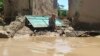 A man sits near his damaged house after heavy flooding in Baghlan province, Afghanistan, on May 12, 2024.