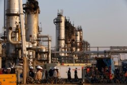 FILE - In this Sept. 20, 2019, file photo, taken during a trip organized by Saudi information ministry, workers fix the damage in Aramco's oil separator at processing facility after the recent Sept. 14 attack in Abqaiq, near Dammam.