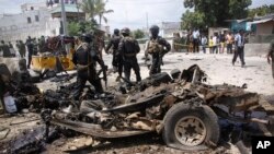 Tentara Somalia berdiri di sekitar bangkai mobil yang digunakan dalam serangan bunuh diri di Mogadishu, Somalia, 31 Juli 2016.