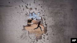 Photo d’archives : Un combattant révolutionnaire libyen court pour se mettre à l'abri lors d’affrontements avec les forces pro-Kadhafi à Syrte, en Libye, vendredi 7 octobre 2011.