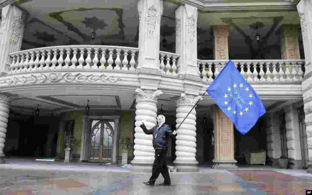Seorang demonstran melambai-lambaikan bendera Uni Eropa di kediaman Presiden Viktor Yanukovych di Mezhyhirya (22/2).
