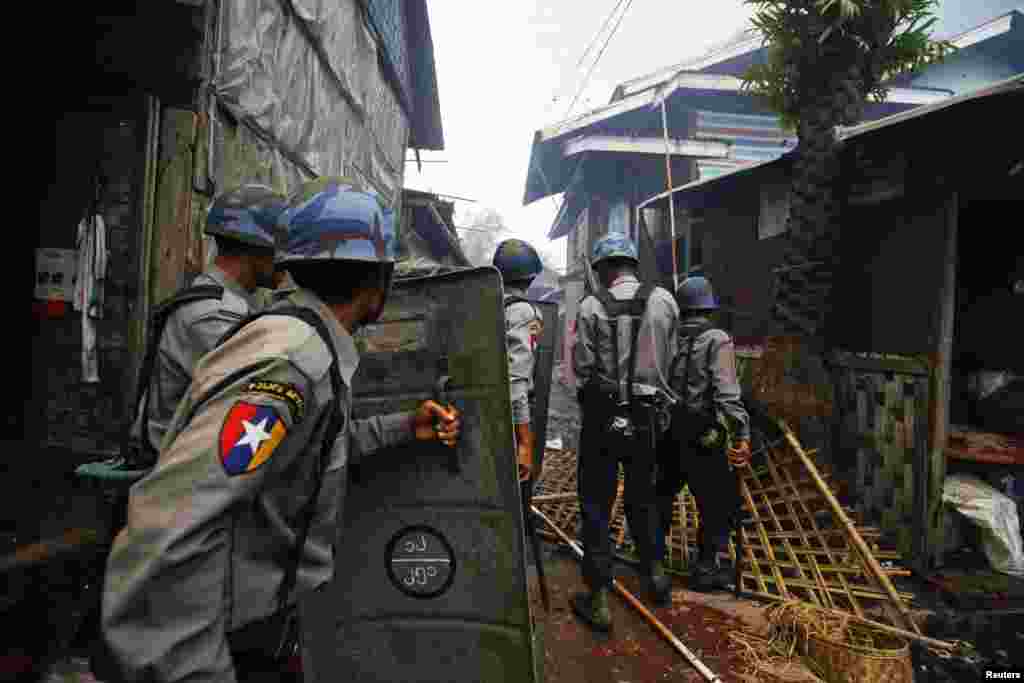 Policemen move towards burning houses during fighting between Buddhist Rakhine and Muslim Rohingya communities in Sittwe, June 10, 2012. 