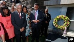 Rev. Julius Scruggs, second from left, leads people in prayer during a wreath laying ceremony at the 16th Street Baptist Church