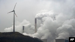 FILE - A wind turbine overlooks the coal-fired power station in Gelsenkirchen, Germany, Dec. 1, 2014. 